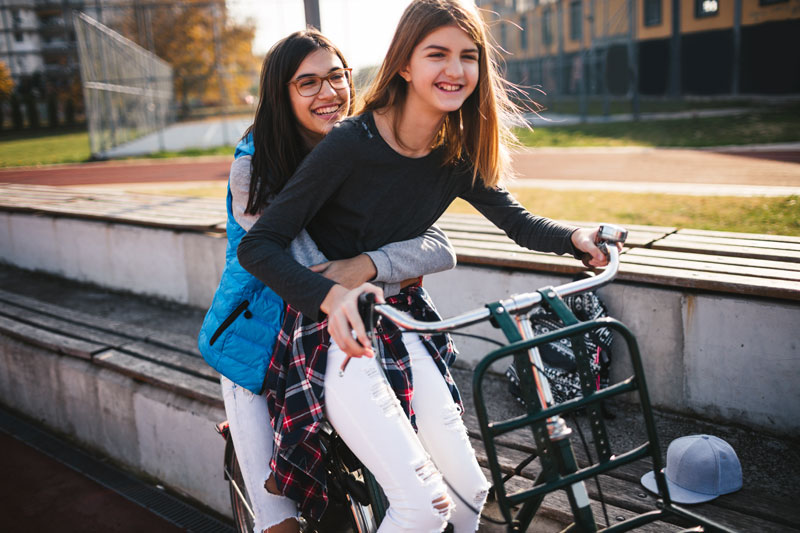 two young women riding in one bicycle